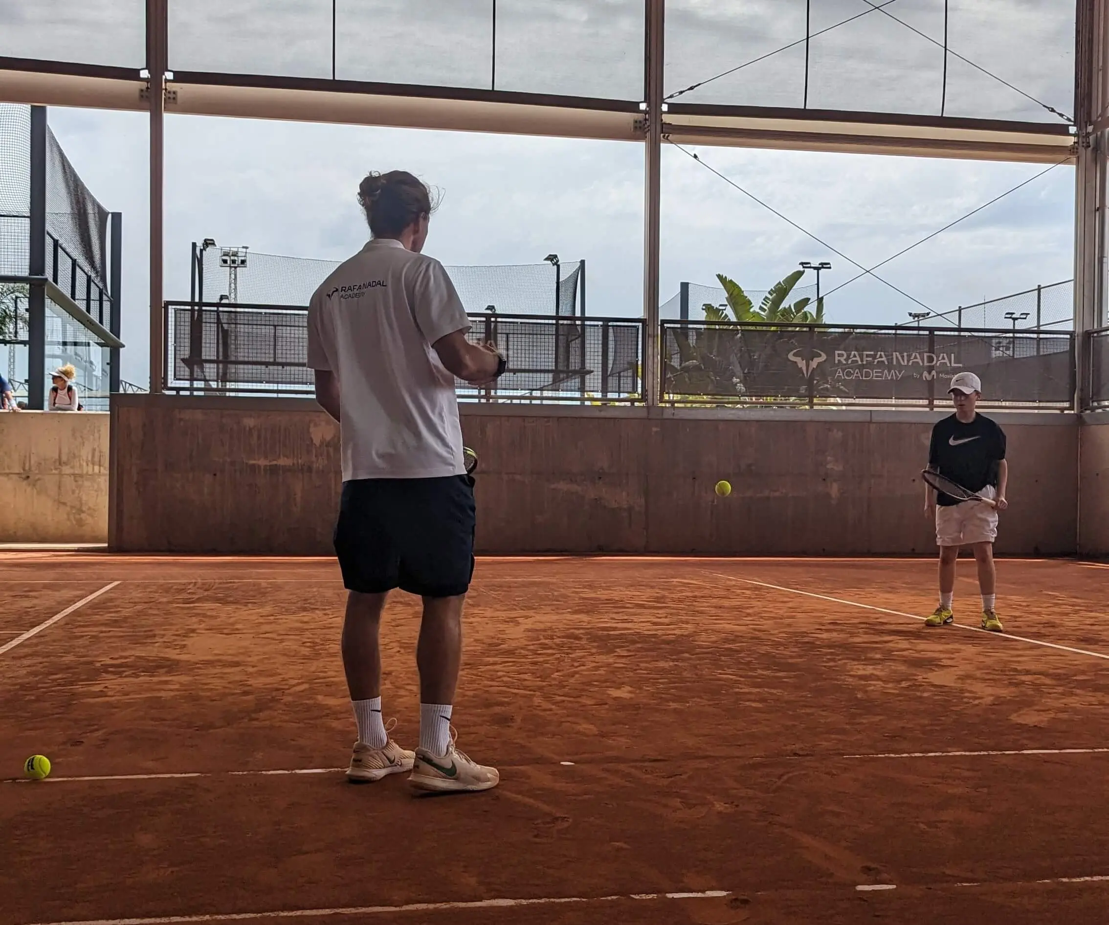 High Performance tennis coach Riccardo Leone instructing a player on a clay court, demonstrating science based tennis training methods in action.
